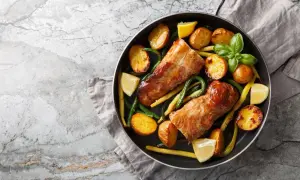 Polędwiczki wieprzowe z pieczonymi ziemniakami i fasolką szparagową, podane na patelni. Idealny obiad.