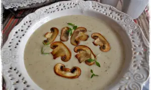 Aksamitna zupa krem z pieczarek z serkiem topionym, udekorowana plasterkami grzybów i gałązką tymianku.