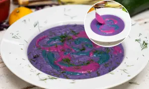 Kremowa zupa z czerwonej kapusty ozdobiona wzorami z różowego i niebieskiego sosu, posypana koperkiem.