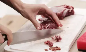 Ręka kroi mięso na desce. Poznaj jak pozbyć się błon i ścięgien z mięsa proste triki, by danie było idealne.