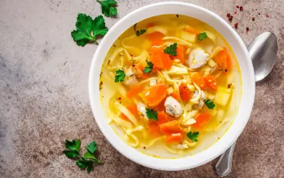 Aromaticzny rosół z indyka z makaronem i marchewką, udekorowany natką pietruszki. Idealny na chłodne dni.