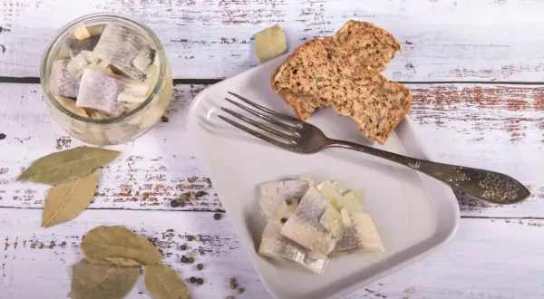 Śledzie z cebulką i chlebem na talerzu. Pytanie, czy w Wielki Piątek można jeść mięso, nie dotyczy tej potrawy.